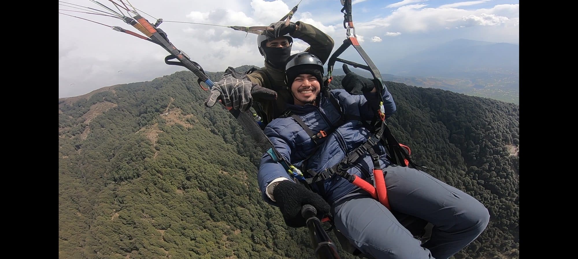 Tandem paragliding high above forested hills at Bir Billing